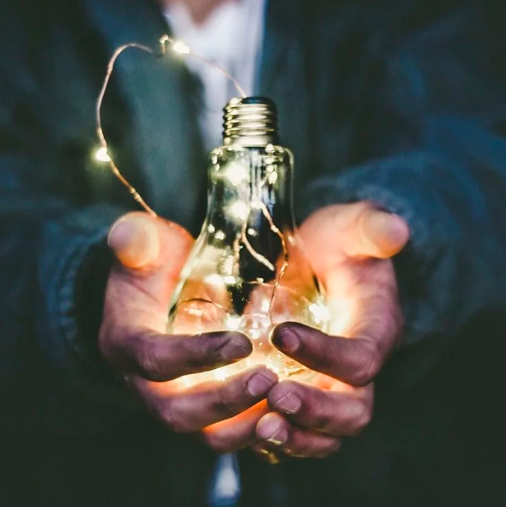 Manos sosteniendo una lámpara iluminada